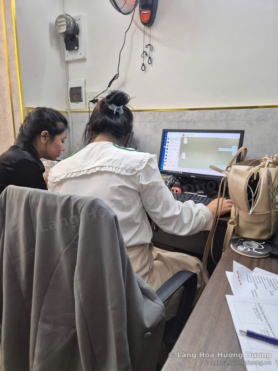 Hai nhân viên ngồi trước máy tính nhận đơn và ghi địa chỉ giao hàng