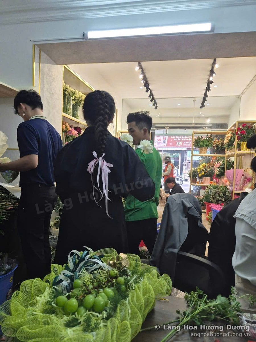 Nhóm nhân viên đứng làm việc trong cửa hàng, trên bàn có giỏ lá xanh
